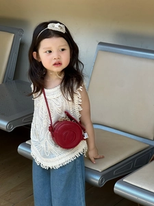 Detail of a red round mini crossbody bag for kids featuring premium lychee pattern leather