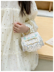 Detail of vintage kids handbag with pearl handle, embroidery, and lace accents