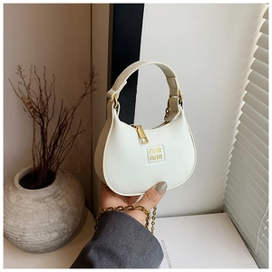 Close-up of a white crescent handbag featuring lychee grain texture and gold hardware