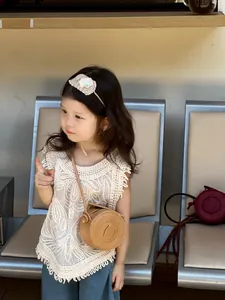Close-up of children's brown round leather crossbody bag with lace tassel vest