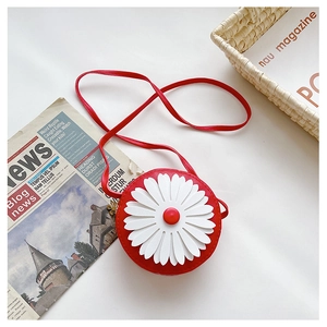 Detailed close-up of a red mini round bag with a white daisy pattern on a white desk