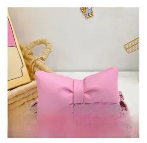 Detail of pink tweed girl's crossbody bag with a large bow and metallic chain strap