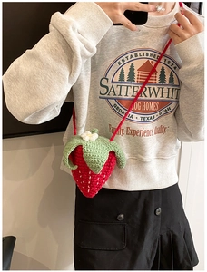 Gros plan du sac bandoulière fraise fait main au crochet avec feuille verte et fleur