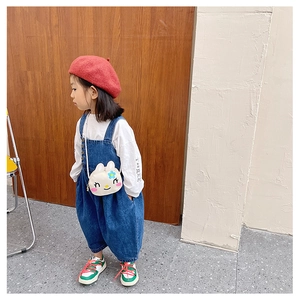 Detail of cute white rabbit shoulder bag styled with navy denim overalls and red beret