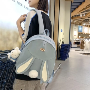 Cute sky blue bunny backpack with 3D ears and plush charm worn by model for daily use