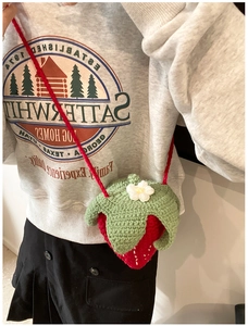 Détail du sac fraise au crochet fait main avec feuille verte et petite fleur blanche