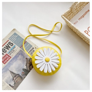 Detail of a bright yellow round mini crossbody bag featuring a white 3D daisy flower