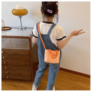 Detail of child wearing an orange canvas crossbody bag with comfortable wide shoulder straps