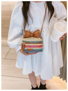 Close-up of rainbow woven kids crossbody bag with large brown bow and gold chain strap