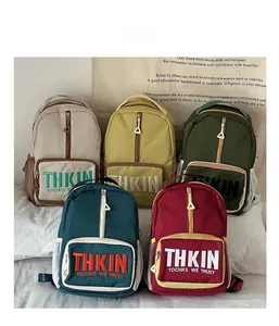 Detailed row of kids backpacks in five colors showing zipper pockets and letter embroidery