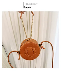 Detail of an orange round mini crossbody bag featuring litchi grain texture and a metal chain