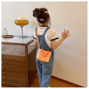 Toddler wearing a bright orange canvas crossbody bag with long strap and top handles