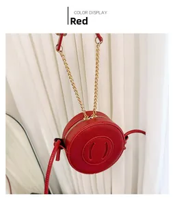 Detail of red circular mini shoulder bag with litchi texture and gold chain strap