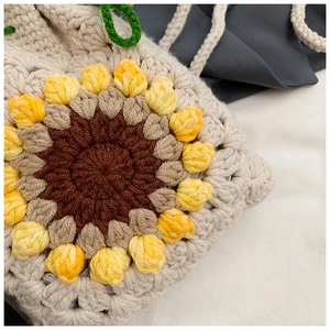 Close-up detail of hand-crocheted sunflower crossbody bag showing knit texture and pattern