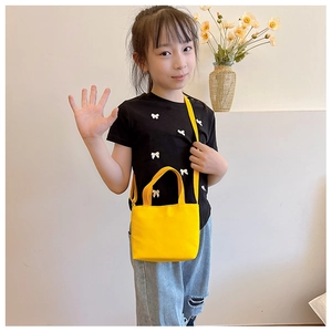 Detail of bright yellow canvas crossbody bag for kids with adjustable strap and top handle