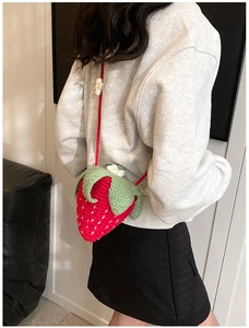 Close-up of handmade crochet strawberry crossbody bag with detailed knit texture and floral accent