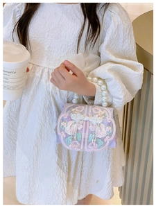 Close-up of girls' purple bag featuring floral embroidery and elegant pearl handle