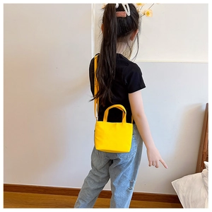 Detail of child wearing a minimalist bright yellow canvas crossbody bag on shoulder