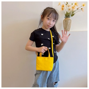 Bright yellow canvas crossbody bag for kids shown being worn by a child model