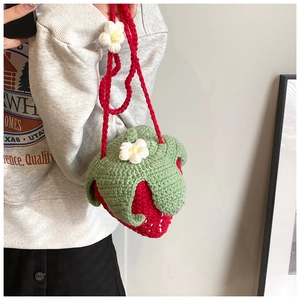 Detail of a handmade red strawberry crochet shoulder bag with white flower accents