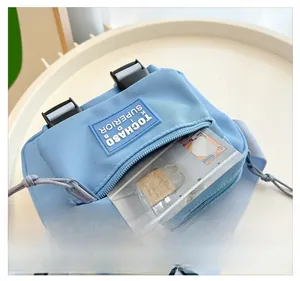 Gros plan détaillé du sac bandoulière en toile bleu clair avec poche avant zippée