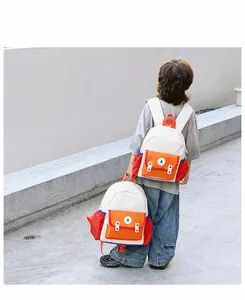 Gros plan du sac à dos enfant bicolore avec poche orange vive et logo arbre vert brodé
