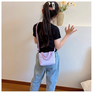 Detail view of a mini purple kids crossbody bag worn by a child in a lifestyle setting