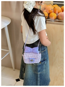 Detail of tweed children's crossbody bag with purple bow and silver metal chain strap