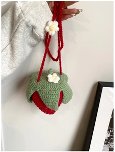 Gros plan détaillé d'un sac à bandoulière fraise au crochet fait main avec feuille tricotée