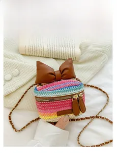 Detailed view of rainbow woven crossbody bag featuring a large brown leather bow detail