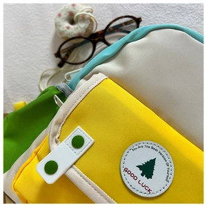Détail du sac à dos coloré montrant l'écusson arbre vert et le slogan Good Luck