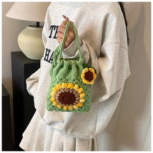 Close-up of green hand-crocheted bucket bag with sunflower pattern and charm detail