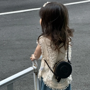 Minimalist black round children crossbody bag styled with a beige crochet knit vest