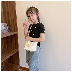 Girl wearing a minimalist cream canvas crossbody bag with top handle and long strap