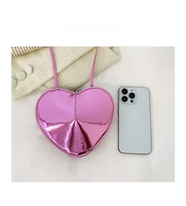 Comparaison de taille d'un mini sac cœur rose métallique avec un smartphone