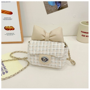 Close-up of beige tweed girls' crossbody bag featuring a large leather bow and chain strap