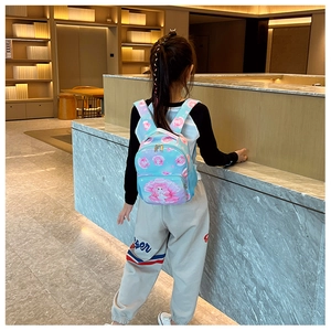 Back view of a child wearing a light blue ocean-themed backpack with pink seashell prints