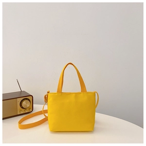 Close-up of bright yellow canvas kids crossbody bag on a white table with vintage radio