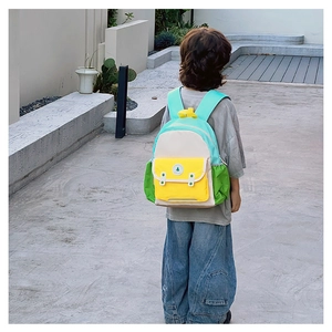 Vue de dos d'un enfant portant un sac à dos coloré aux empiècements bleu et jaune