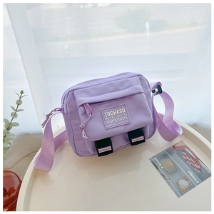 Détail du sac bandoulière enfant en nylon lavande avec rabat à boucle et étiquette tissée