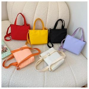 Flat lay of small canvas crossbody bags for kids in six vibrant colors with adjustable straps