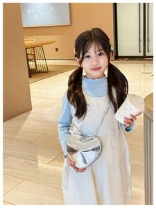 Détail du sac bandoulière argenté en forme de cœur sur une tenue enfant stylée