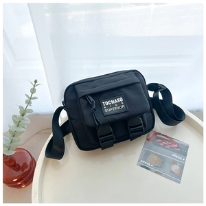 Détail d'un sac bandoulière noir pour enfant en toile avec boucles sur plateau blanc