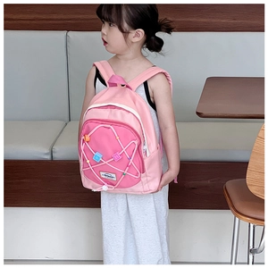 Detailansicht eines rosa Rucksacks mit Kordelzug und bunten geometrischen Schiebern