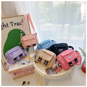 Détail de mini sacs bandoulière en toile colorée avec bretelles réglables et logo