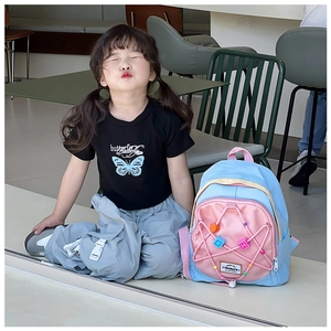 Detail eines farblich abgesetzten Kinderrucksacks mit Sternanhängern am jungen Model