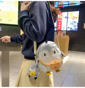 Detailed view of the cute penguin crossbody bag with a plush charm on a child model