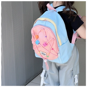 Detail bunter Perlen und gewebter Kordel am hellblauen Kinderrucksack mit rosa Tasche