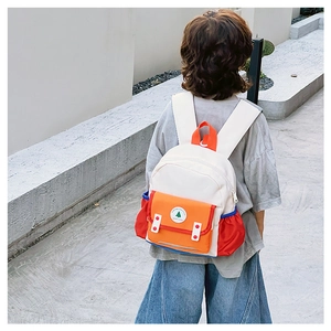 Vue arrière d'un enfant portant le sac à dos color-block devant un mur blanc épuré