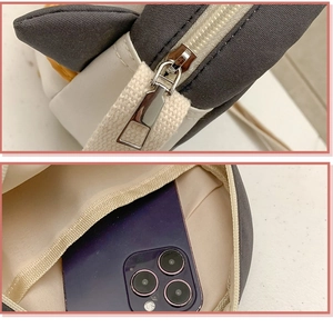 Detail view of penguin crossbody bag showing zipper quality and internal phone storage capacity